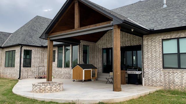A brick house with a covered patio and a dog house in front of it.