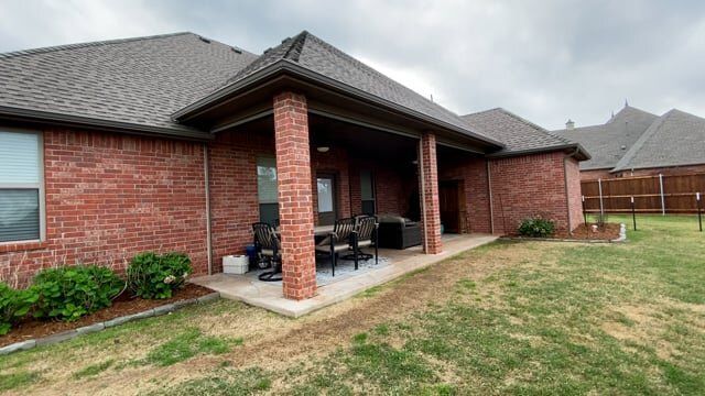 A brick house with a patio and a fence in the backyard.