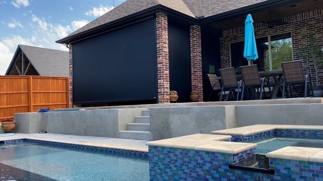 There is a swimming pool in the backyard of a house.