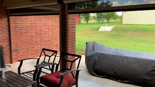 A patio with chairs , a table and a motorcycle cover.