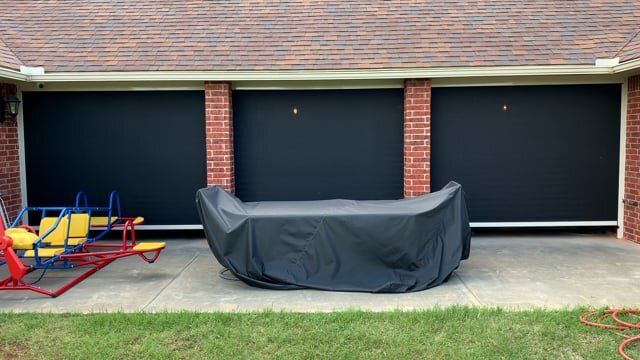 A black cover is covering a table in front of a garage door