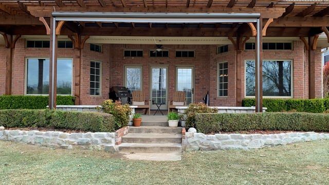 A large brick house with a large porch and stairs leading to it.
