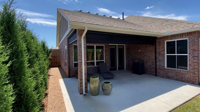The backyard of a brick house with a patio and potted plants.