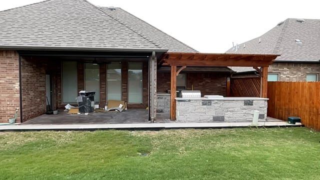 A brick house with a pergola and a grill in the backyard.