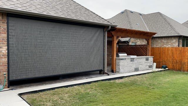 A house with a screened in porch and a grill in the backyard.