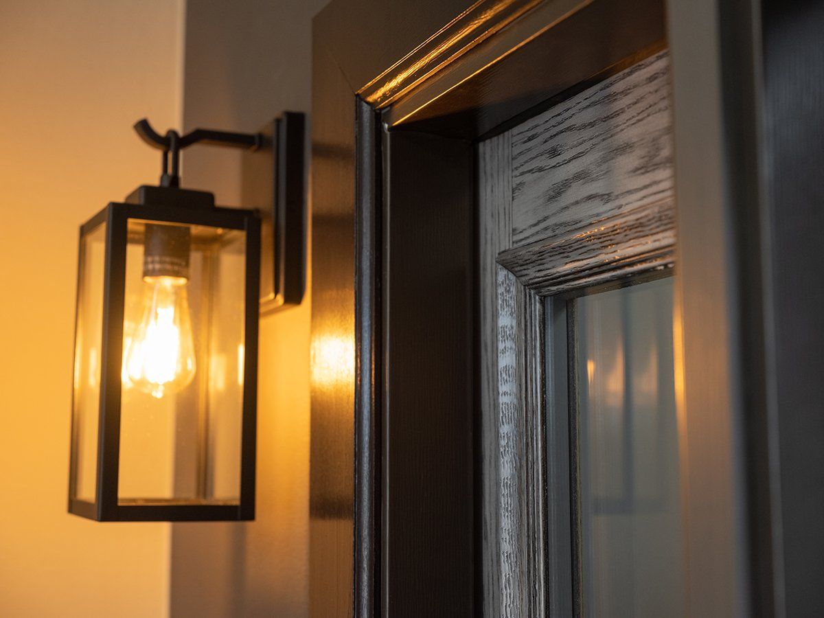 A lantern is hanging on a wall next to a door.