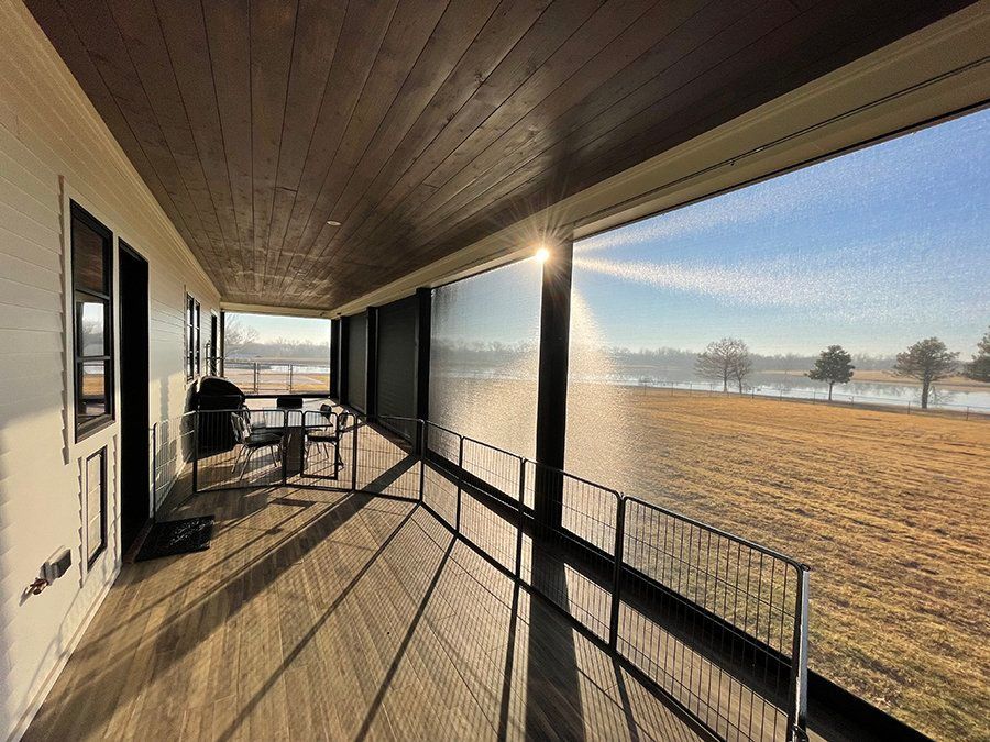 A large screened in porch with a view of a field.