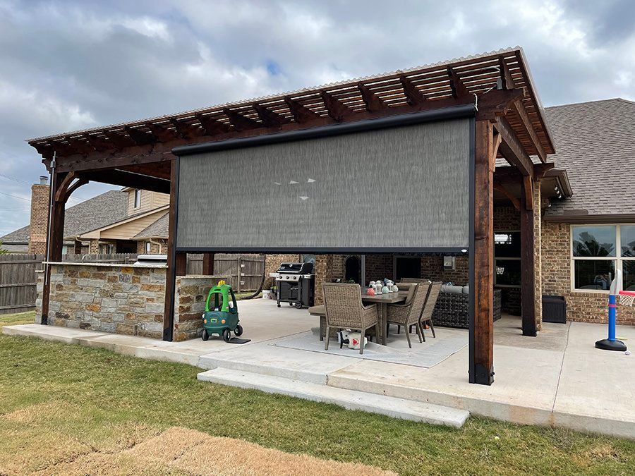 A patio with a pergola and a table and chairs underneath it.