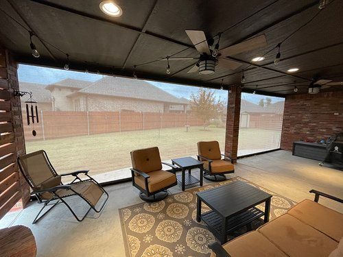 A living room with a couch , chairs , tables and a ceiling fan.