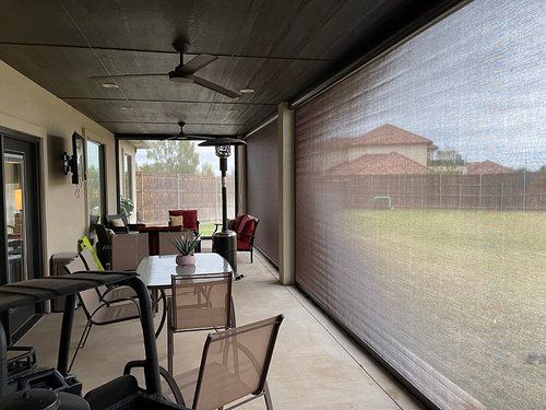A screened in porch with a table and chairs and a golf cart.