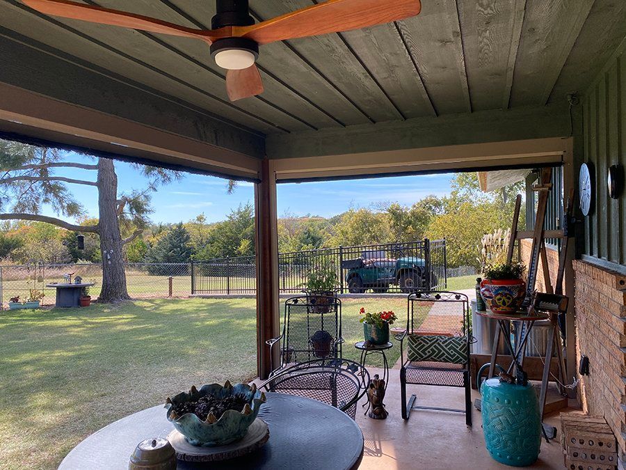 A porch with a table and chairs and a ceiling fan.