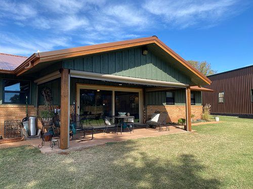 A house with a green roof and a covered patio in front of it.