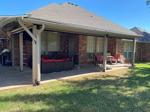 A brick house with a covered patio in front of it.