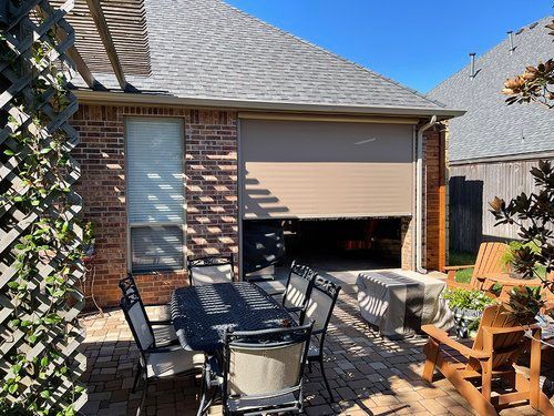 A patio with a table and chairs in front of a garage door.