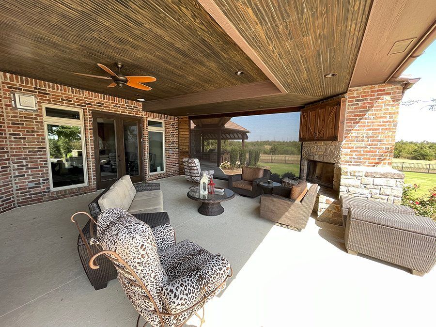 A large patio with a fireplace and a ceiling fan.