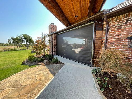 A brick house with a screened in porch and a walkway leading to it.