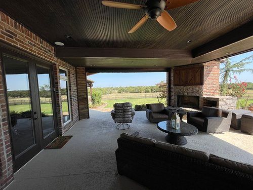 A large covered patio with a ceiling fan and a fireplace.