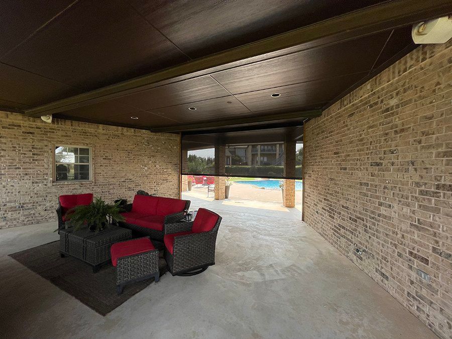A patio with a couch , chairs , ottomans and a table.