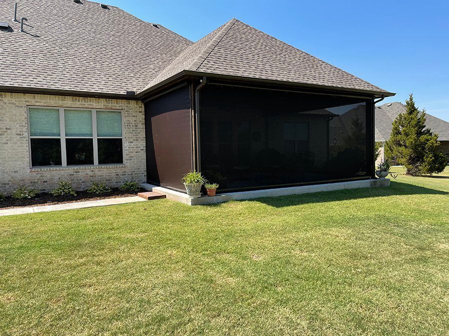 A house with a screened in porch and a large lawn in front of it.