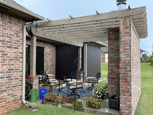 There is a pergola in the backyard of a brick house.