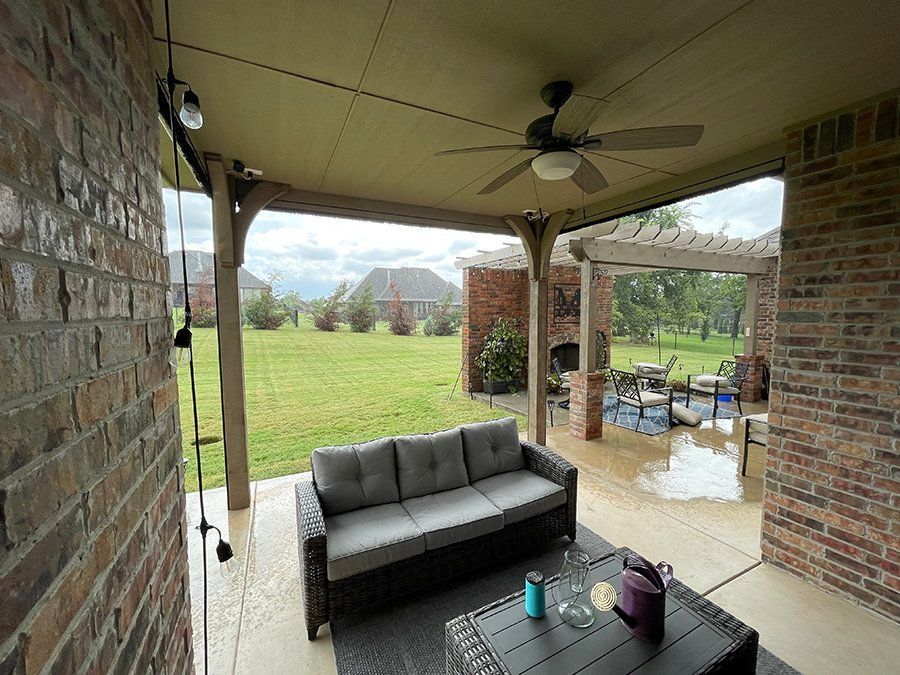 A patio with a couch , table , and ceiling fan.