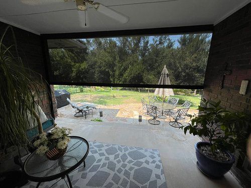 A screened in porch with a table and chairs and a view of the backyard.