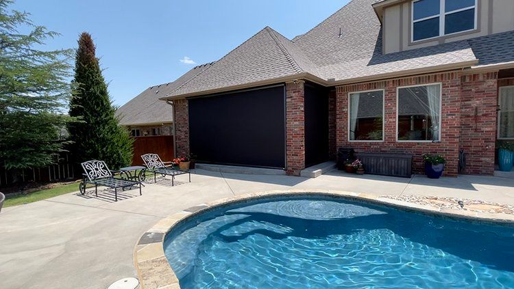 There is a large swimming pool in the backyard of a house.