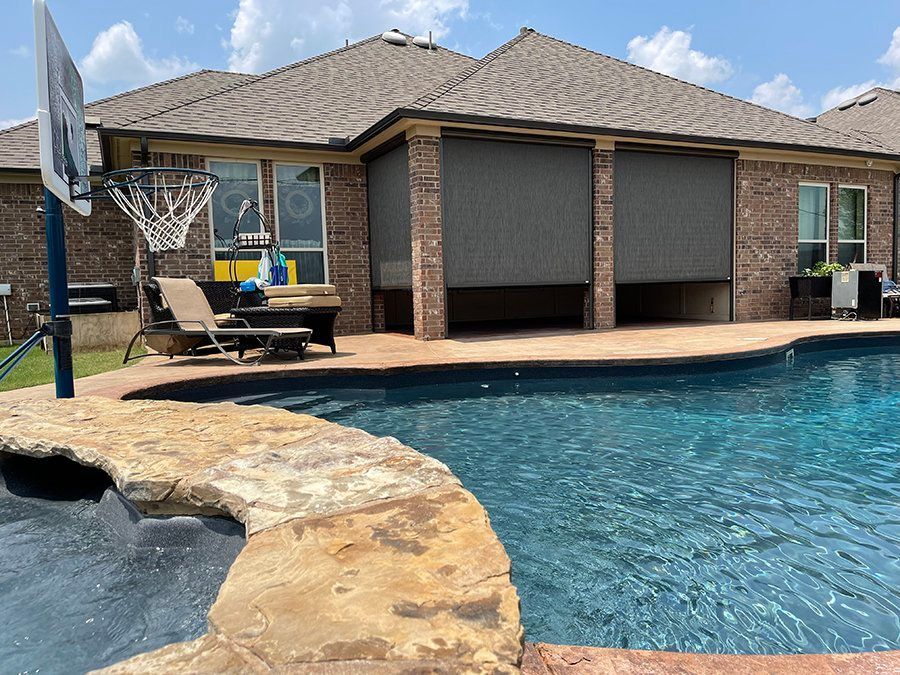 A house with a pool and a basketball hoop in front of it.