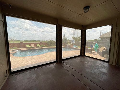 A screened in porch with a view of a swimming pool.
