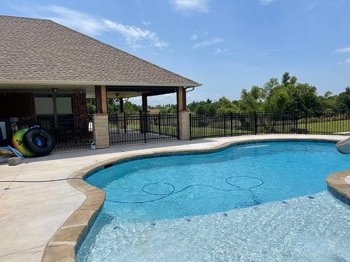 There is a large swimming pool in front of a house.