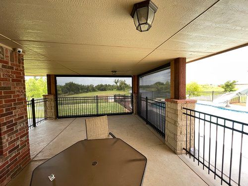 A screened in porch with a table and chairs and a pool in the background.