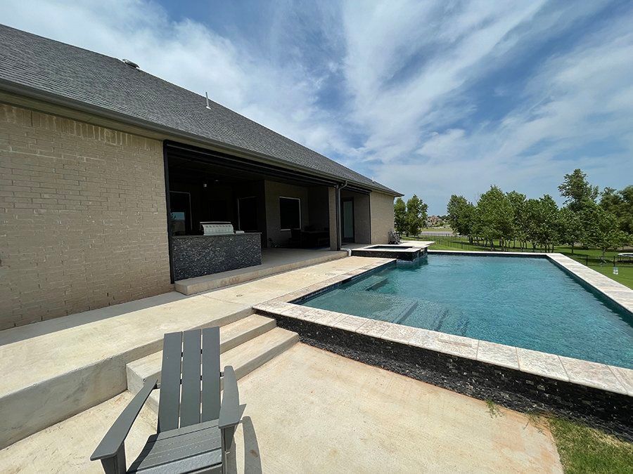 A large swimming pool is in the backyard of a house.