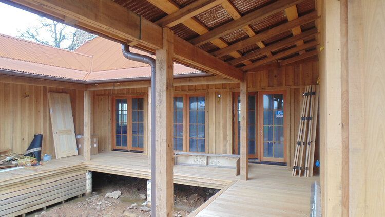 A wooden house with a wooden deck and a roof.