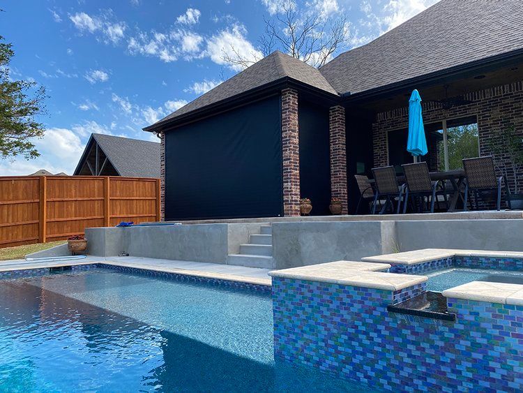 There is a large swimming pool in the backyard of a house.