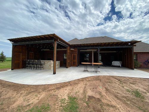 A large house with a covered patio and tables in front of it.