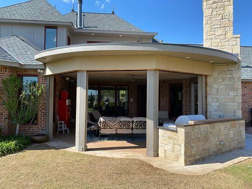 A large brick house with a covered patio and a grill.
