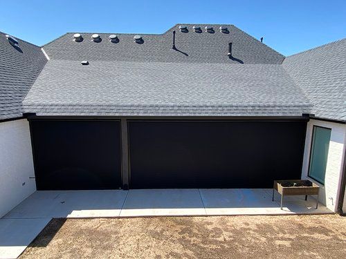 An aerial view of a house with a black garage door and a gray roof.