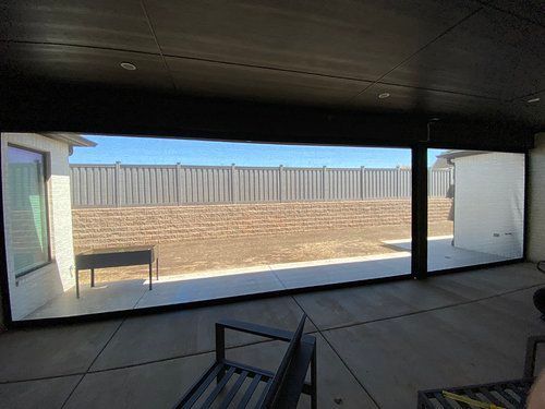 A large screened in porch with a fence in the background.