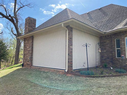 A large white garage door is on the side of a brick house.