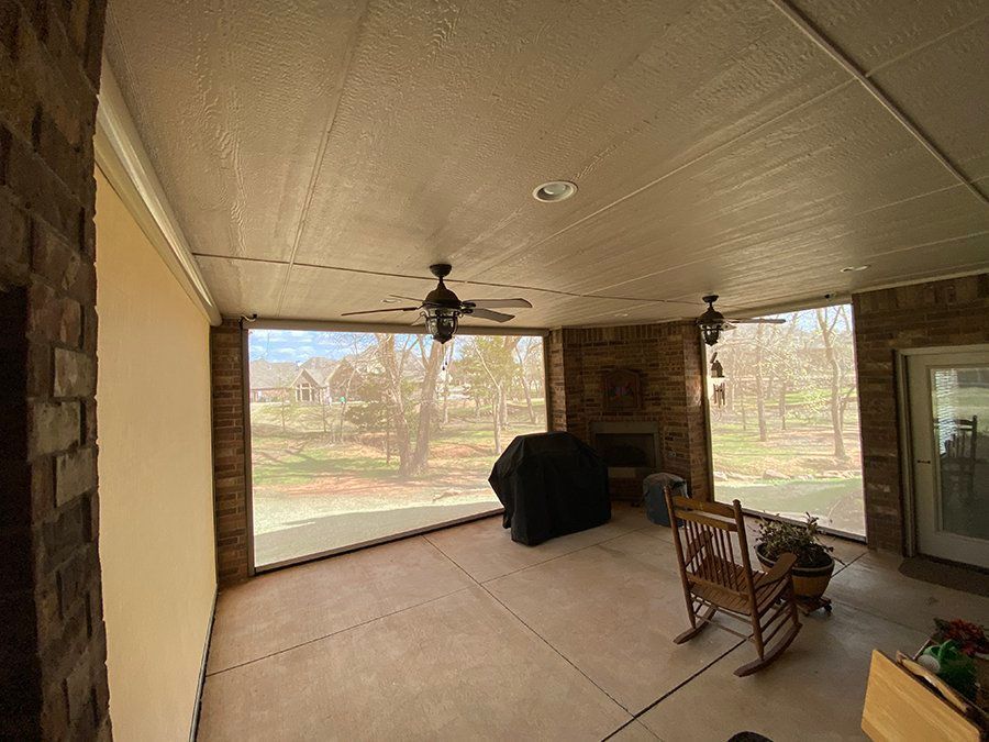A screened in porch with a rocking chair and a ceiling fan.