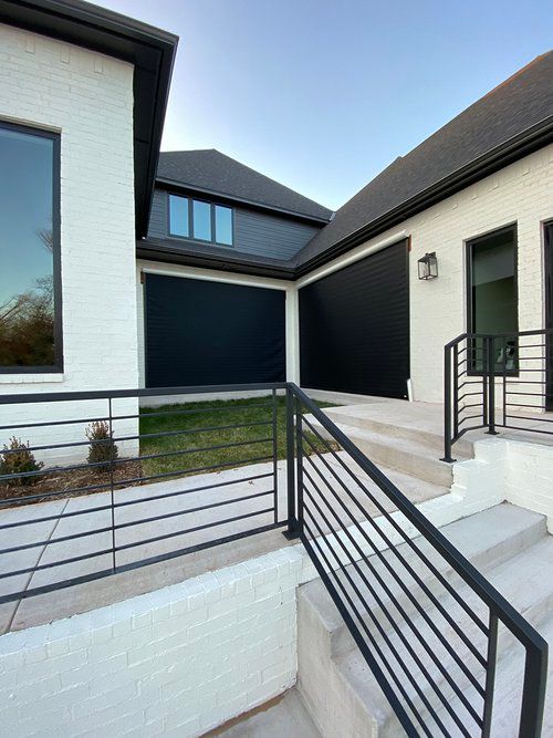 A white house with black garage doors and stairs leading up to it.