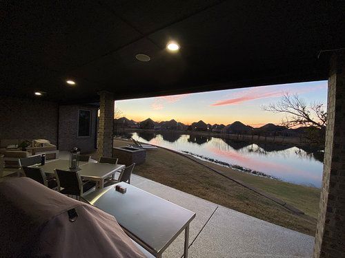 A patio with a view of a lake and a table and chairs.