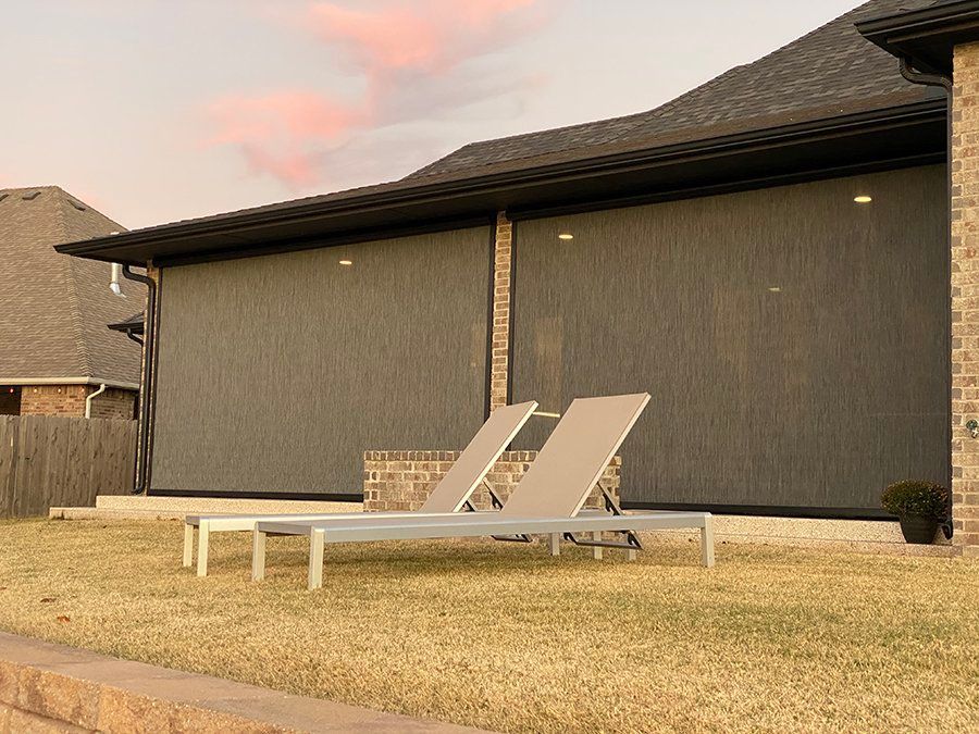 There are two lounge chairs in the backyard of a house.