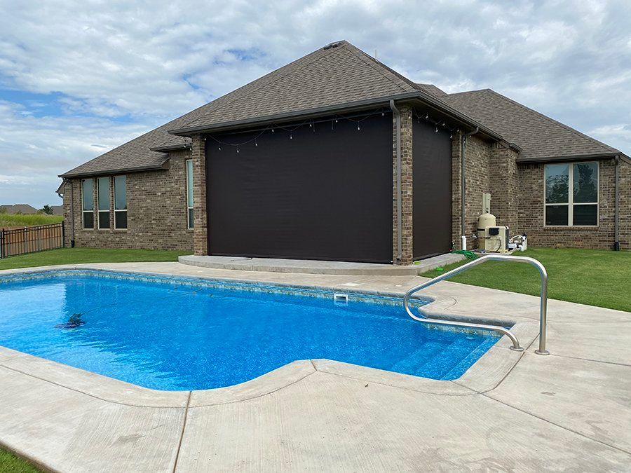 There is a large swimming pool in the backyard of a house.