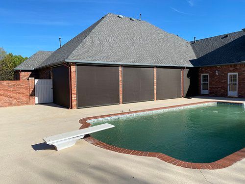 There is a large swimming pool in the backyard of a house.