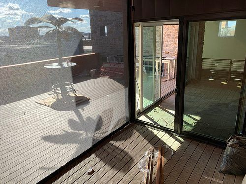 A balcony with a sliding glass door and a table and chairs on it.