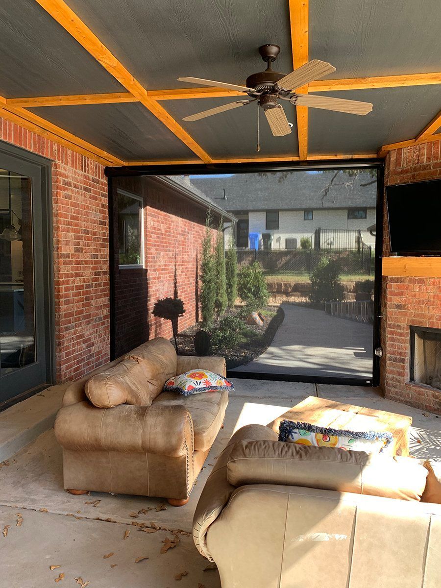 A living room with a couch and chairs and a ceiling fan.