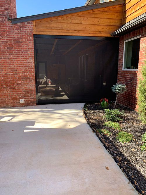 A screen door is installed on the side of a brick house.
