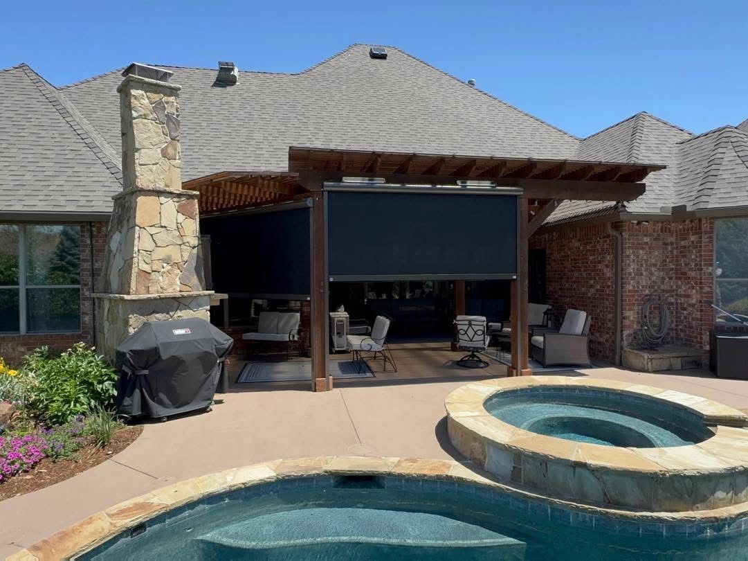 Backyard patio with pergola, pool, hot tub, and retractable black screens for shade.