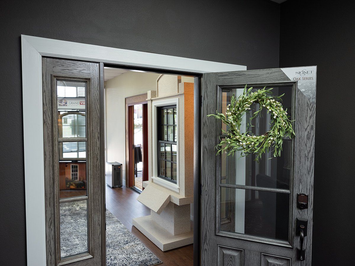 A door with a wreath on it is open to a room with a lot of windows.